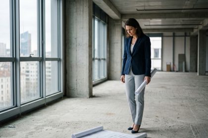 Femme professionnelle examinant des plans d'aménagement dans un espace de bureaux vide à Lyon avant installation