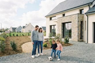 Famille heureuse devant leur maison neuve à Créhen