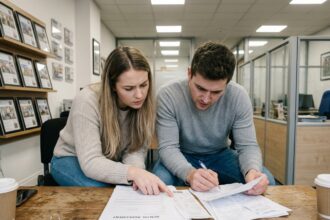 Jeune couple examinant des documents immobiliers dans une agence